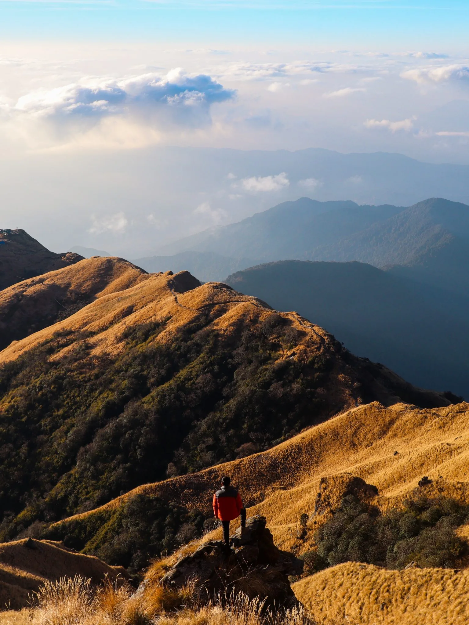 A person on a mountain ridge looking toward the journey ahead